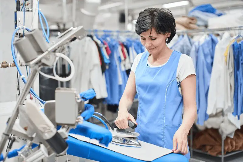 Woman ironing clothes at a laundry facility.